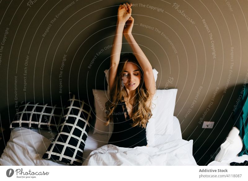 Young woman waking up in morning wake up bed stretch smile arms raised comfort bedroom home female young nightwear sleepwear relax cozy rest beautiful lifestyle