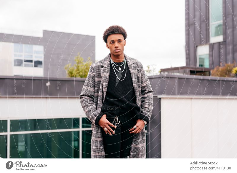 Confident young man in trendy coat standing on street style fashion urban cool model city building autumn serious modern african american black ethnic confident
