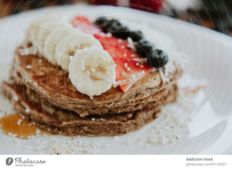 Pancakes decorated with banana and strawberries with blueberries and coconut pancake breakfast sweet serve table strawberry blueberry flake diet plate stack