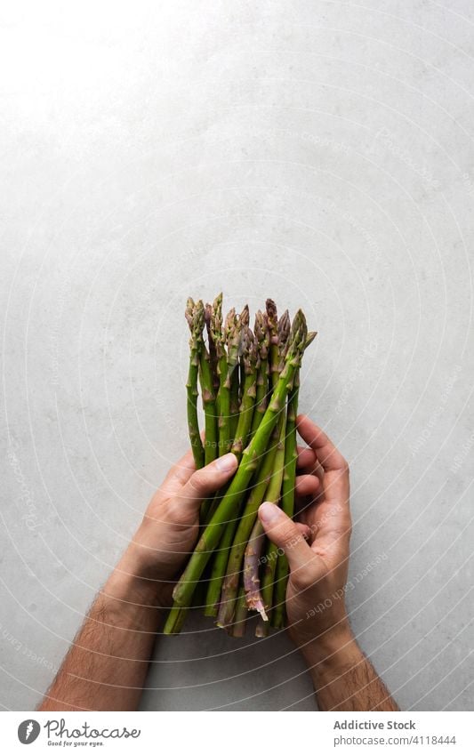 Cook holding bunch of fresh asparagus green healthy vegetarian table food hand kitchen raw cook chef plant meal diet cuisine herb prepare vegetable ingredient