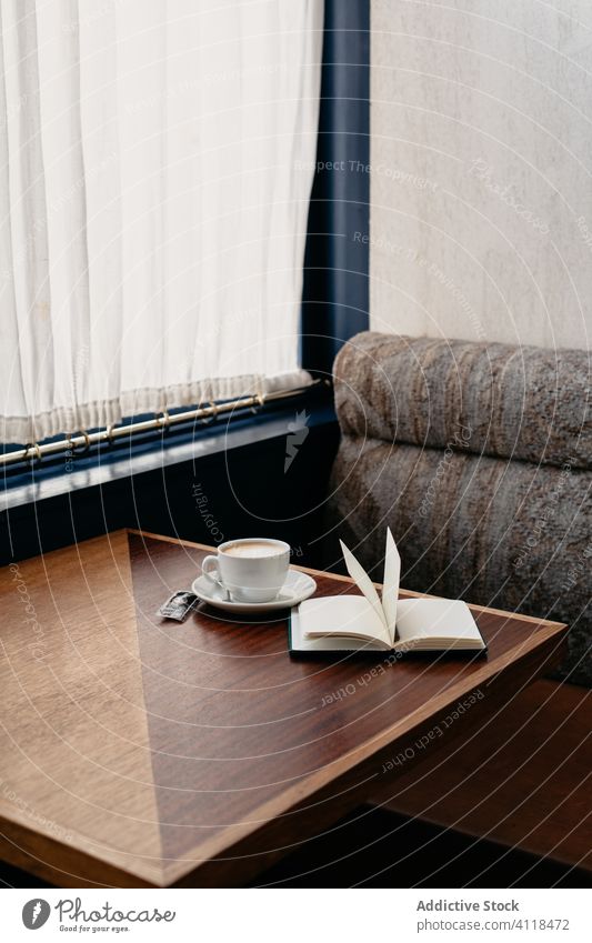 Close-up of a cup of coffee and a book on a table notebook cafe bar drink restaurant tea wooden businesswoman interior sofa alone