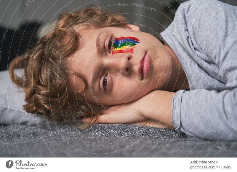 Boy with rainbow on face lying on floor boy home quarantine concept symbol blanket pillow kid child pandemic epidemic rest relax isolation adorable cute alone