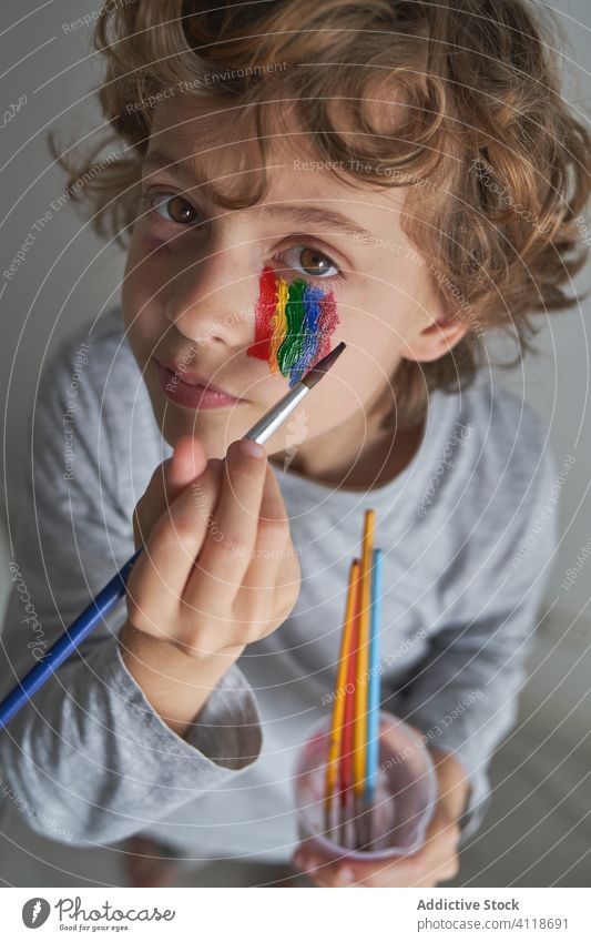 Boy painting rainbow on face boy home quarantine concept brush symbol kid pandemic child epidemic rest relax isolation adorable cute coronavirus covid 19