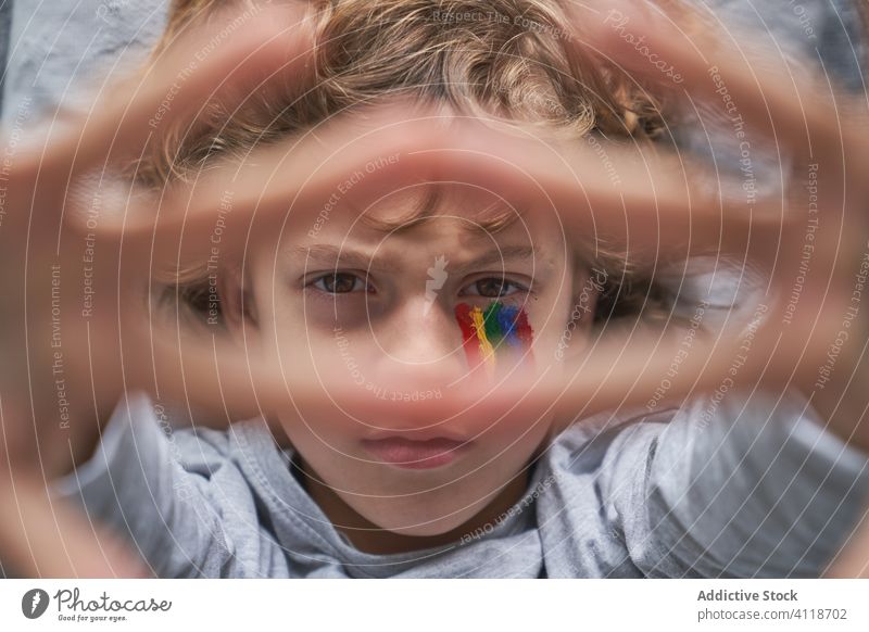 Serious boy with rainbow showing hands with Stay Home writing quarantine stay home stop concept gesture symbol lying floor blanket pillow kid child pandemic
