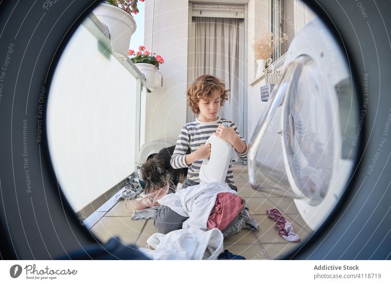 Kid with dog having fun in laundry room kid wash machine messy playful cloth home pet together smile boy housework cheerful household domestic clean child