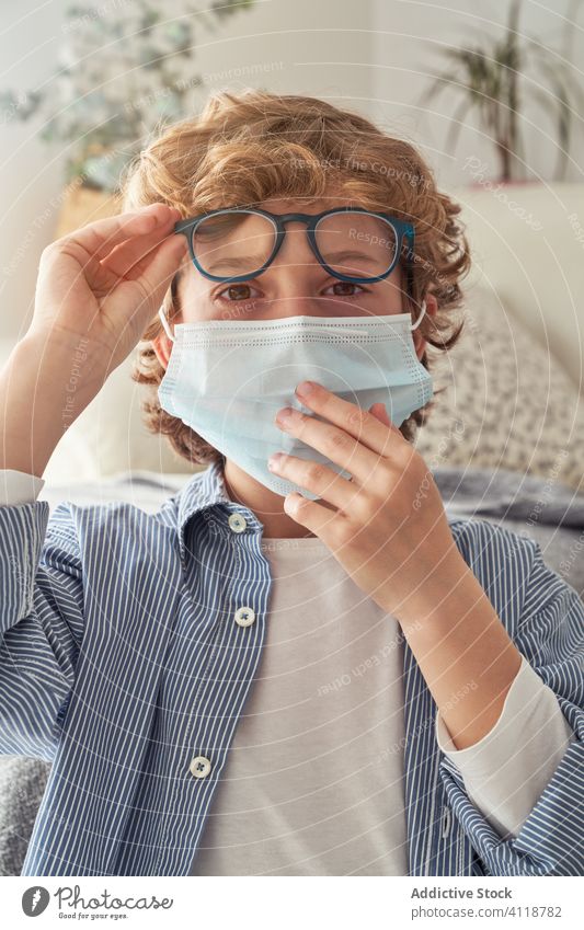 Boy putting on glasses before remote studies boy education quarantine put on prepare mask notebook table home kid child study lifestyle prevent notepad sit