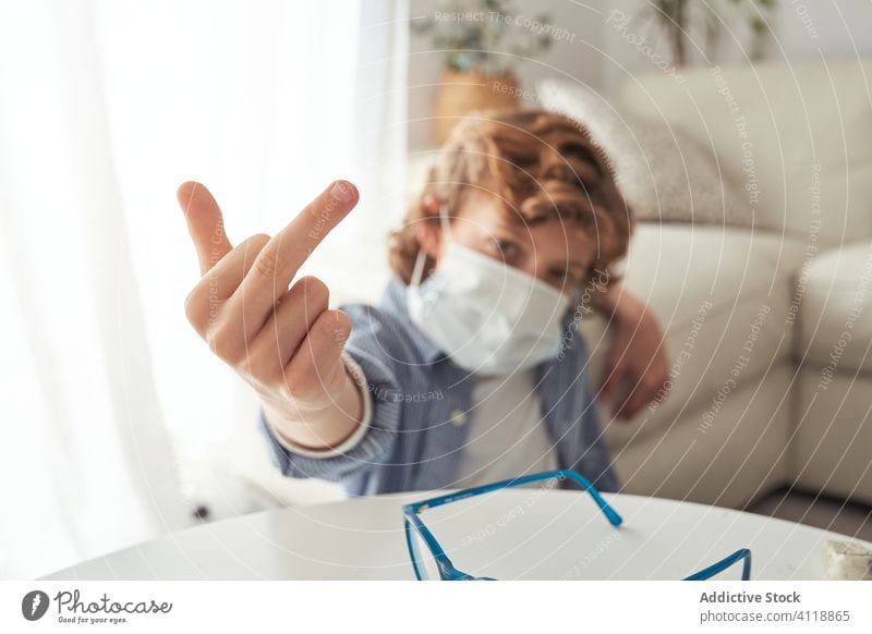 Boy showing middle finger during quarantine boy gesture home medical mask pandemic coronavirus fuck prevent modern kid child protect rude covid 19 glasses