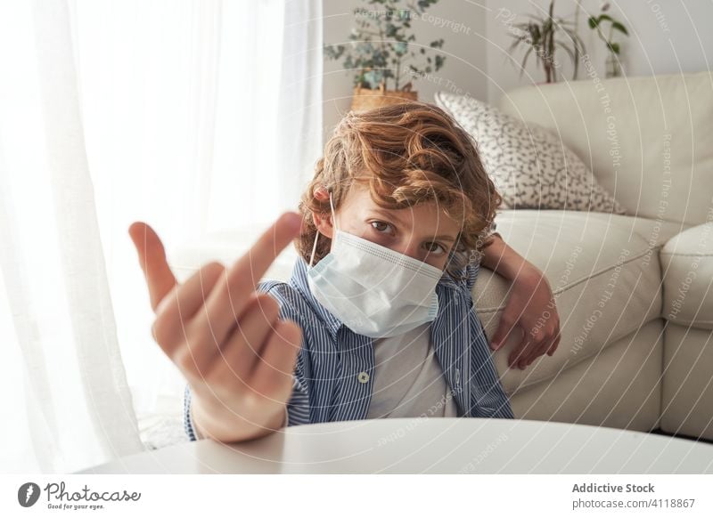 Boy showing middle finger during quarantine boy gesture home medical mask pandemic coronavirus fuck prevent modern kid child protect rude covid 19 health care