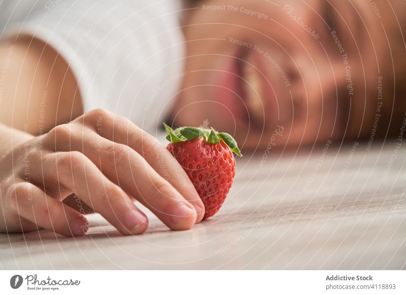 Happy child playing with strawberry on floor home happy summer weekend rest ripe kid lying cheerful food fruit smile game healthy sweet fresh childhood little