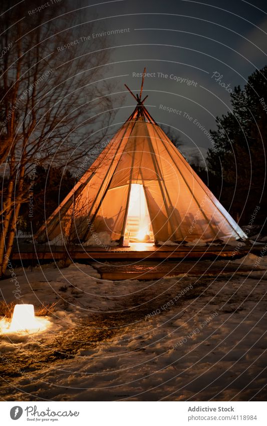 Solitary touristic teepee tent with campfire inside in snowy forest at cold winter night tourism travel evening trip flame nature solitude recreation lofoten