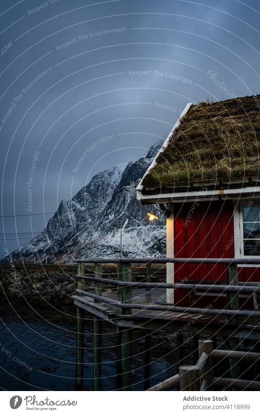 Small country house on lake in winter cottage pier shore foothill waterfront sky snow township countryside coast lofoten idyllic facade shoreline tranquil