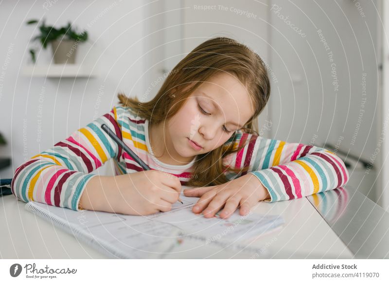 Girl making homework at table girl write notebook smart study focus sit kid child school student notepad pencil education serious pupil lifestyle diligent memo