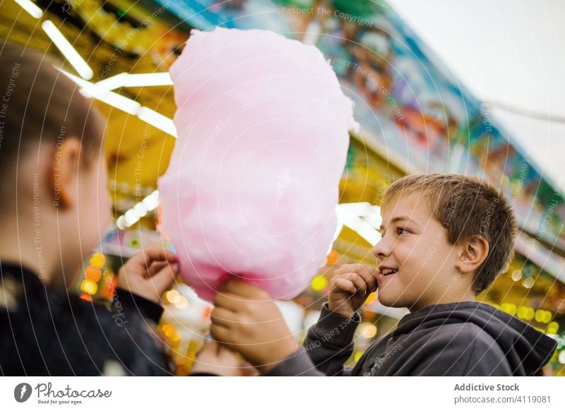 Kids eating cotton candy on funfair candyfloss smile lights city entertainment kid happy child urban sweet delighted treat boy lifestyle cheerful little sugar