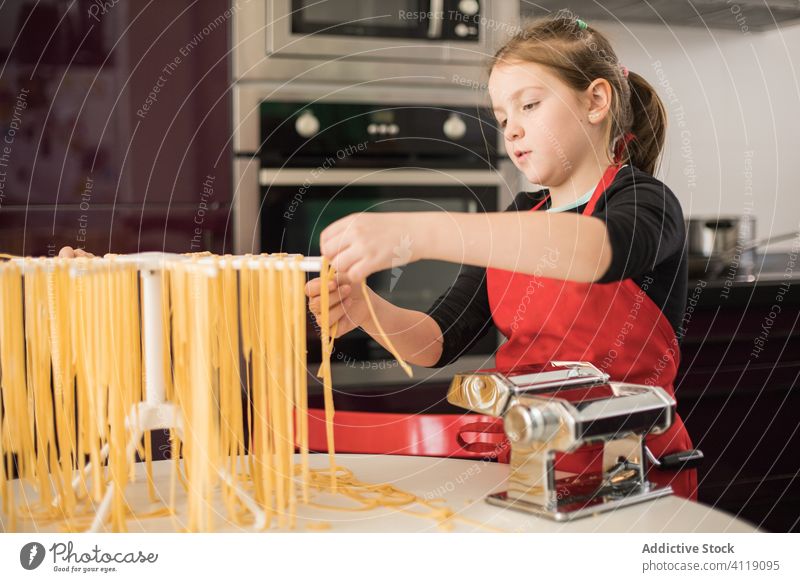 Little girl making pasta in kitchen kid make dry hang machine prepare noodle food learn apron female child serious cook rack culinary fresh equipment homemade