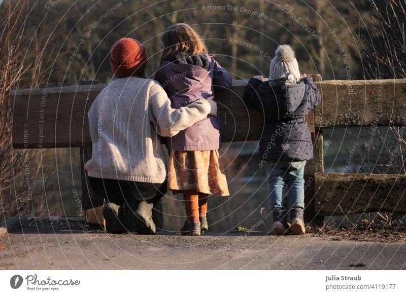 The three girls from the gas station children Wait look inquisitorial Observe Control barrier Fence Wooden fence Tip of the toe early Cold Sunlight Evening sun