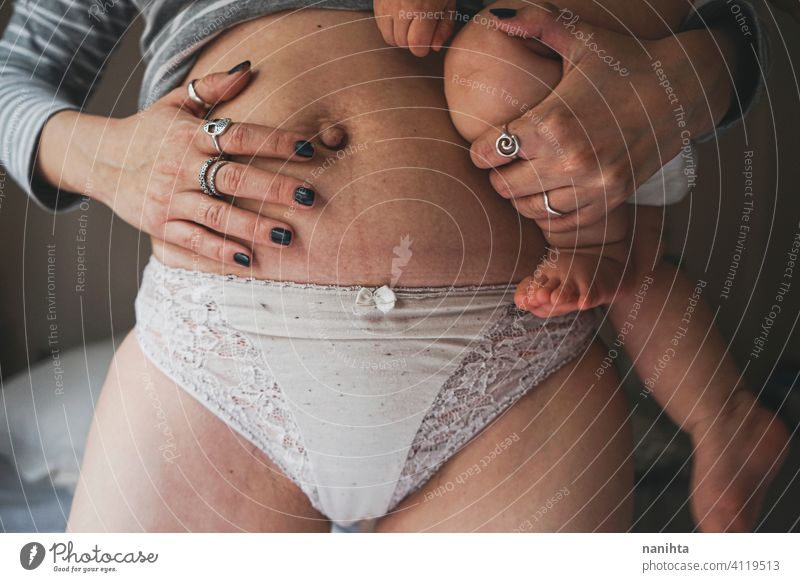 Real image of a woman and her baby at postpartum recovery childbirth motherhood real body positive people mom home quarantine belly belly button pregnancy