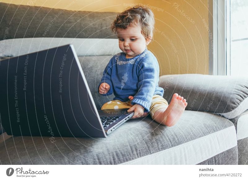 Little baby at home playing with a laptop technology progress future sofa furniture pc computer risk wifi social media new generation babyhood screen childhood