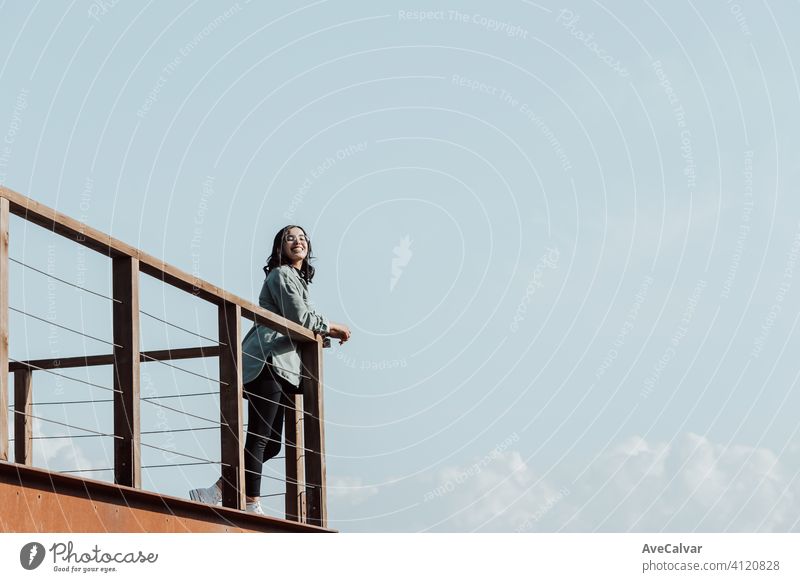 Woman in a balcony over a massive river and the mountains living the moment liberty and freedom concept, wellness during a sunny day white copy-space 20s 30s