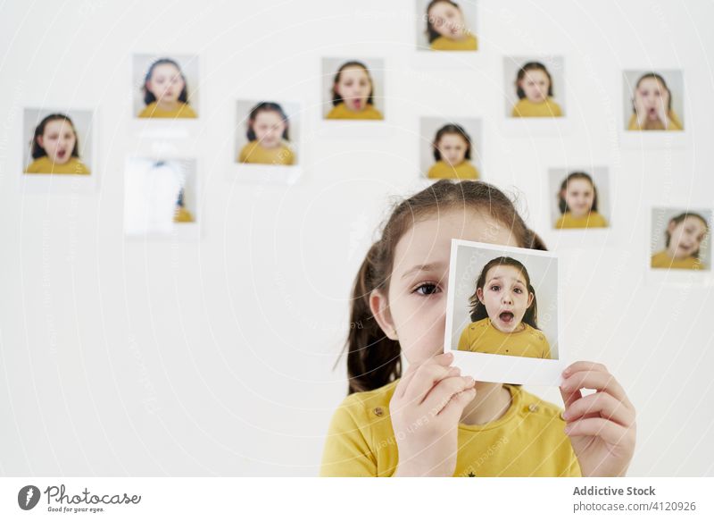 Little girl with own instant photos kid child picture various wall covering face expressive casual little set creative photography cute portrait image shot