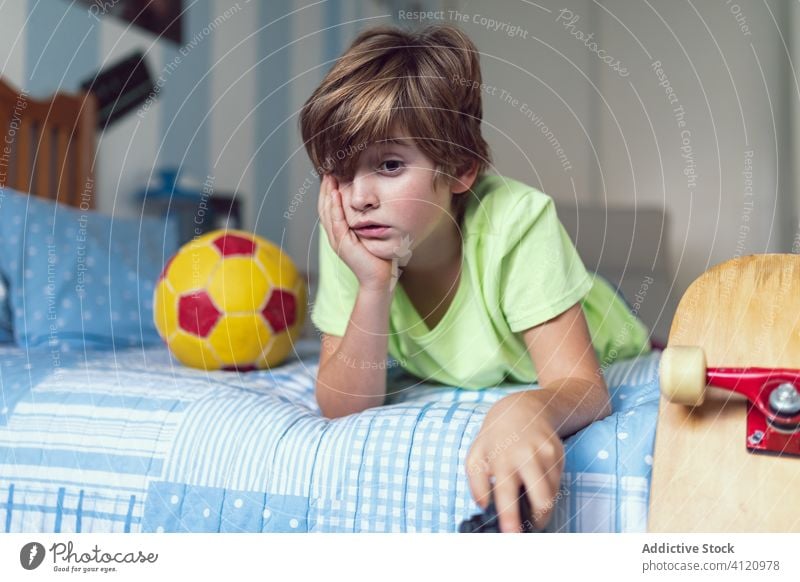 Bored kid spending time in bedroom home bored sad alone unhappy isolation tired boy upset child toy little childhood lifestyle rest male thoughtful serious