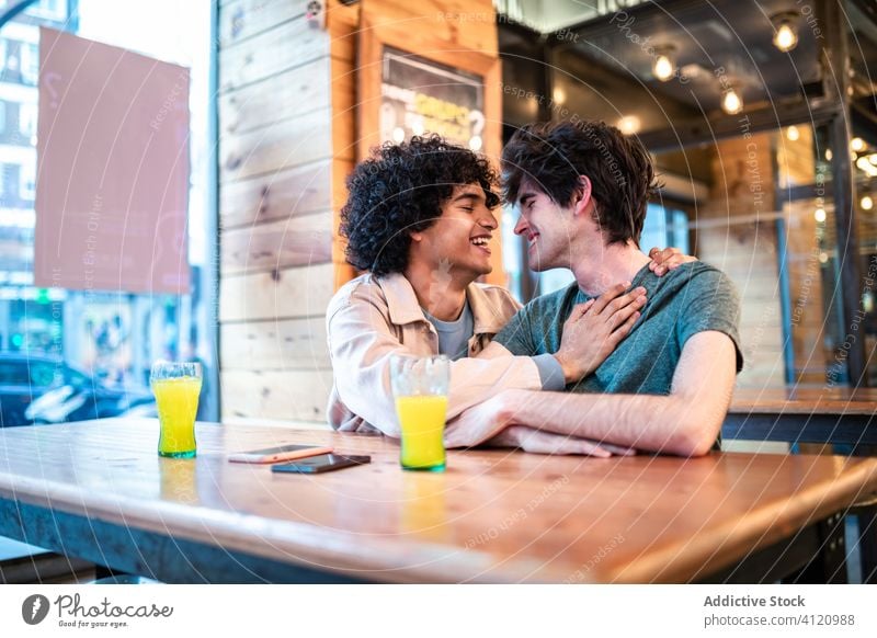 Multiethnic gay couple flirting during date in cafe table happy together cheerful friend boyfriend romantic affection partner kiss homosexual lover lgbt