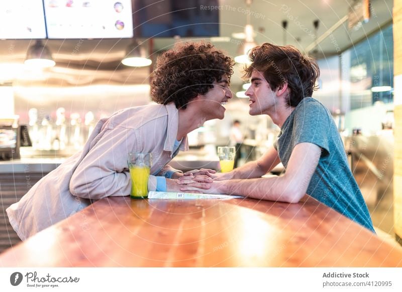 Multiethnic gay couple flirting during date in cafe table happy together cheerful friend boyfriend romantic affection partner homosexual lover lgbt same sex
