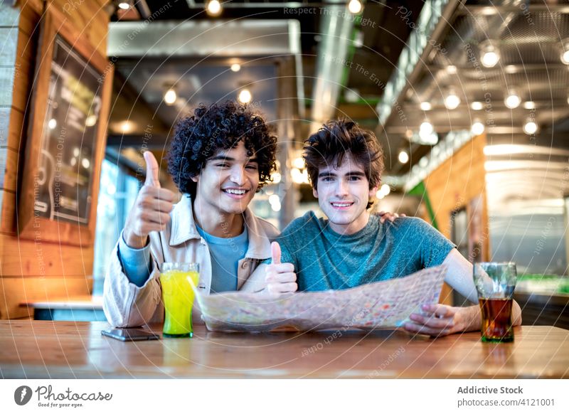 Gay couple gesturing thumb up while checking map gay date cafe smile gesture drink diverse men young happy cheerful together boyfriend partner love romantic