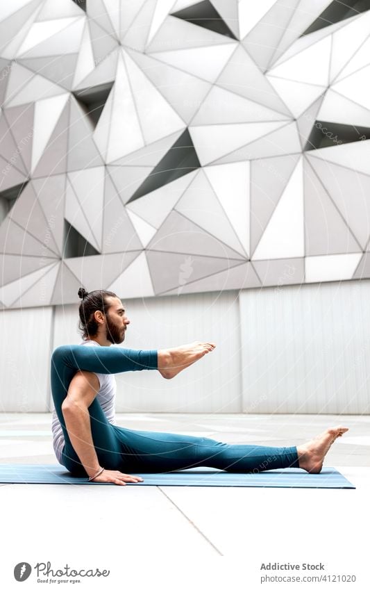 Flexible man doing yoga exercise training geometry asana flexible modern stretch fitness shape male sportswear architecture contemporary wall spacious zen
