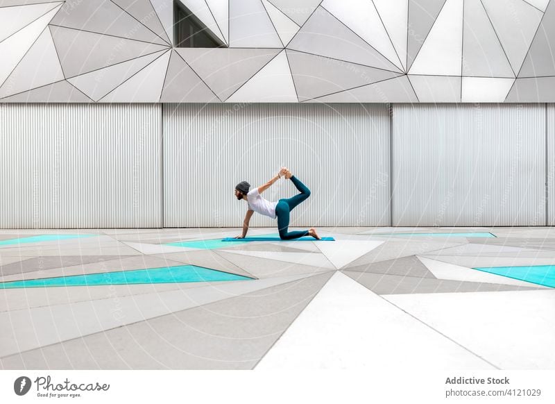 Man doing yoga in spacious room man exercise training geometry modern stretch fitness shape male sportswear architecture contemporary wall zen balance workout