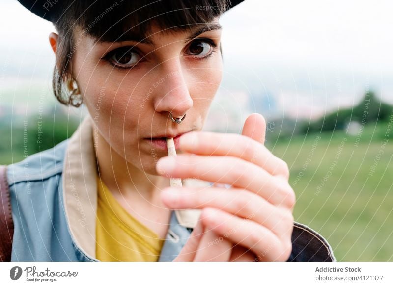 Young lady smoking cigarette on street woman cool smoke habit piercing human face subculture informal modern makeup nose addict tobacco young casual nicotine