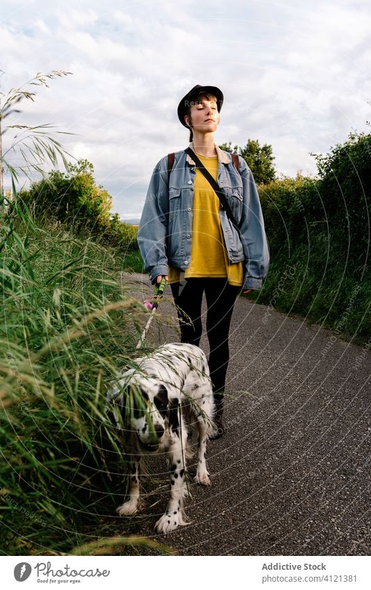Woman walking with dog on road in countryside woman park nature calm fresh air enjoy peace companion stroll together friend grass green young path pet leisure