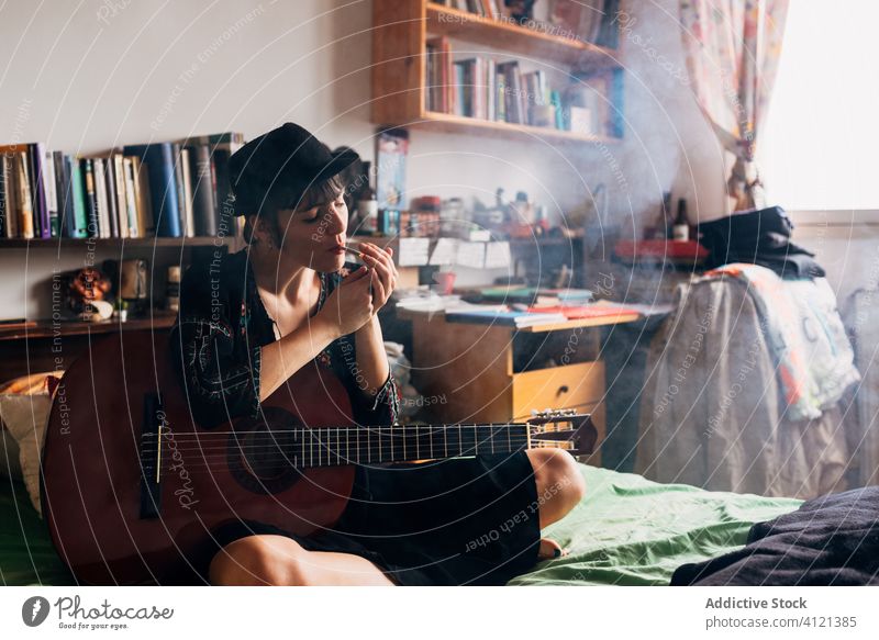 Female hipster with acoustic guitar smoking weed at home smoke woman relax marijuana guitarist female music instrument serene style calm tranquil trendy melody