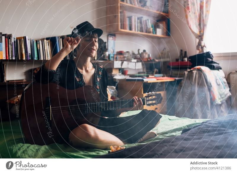Female hipster with acoustic guitar smoking weed at home smoke woman relax marijuana guitarist female music instrument serene style calm tranquil trendy melody