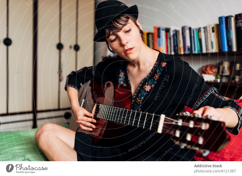 Calm woman playing guitar in bedroom music acoustic instrument calm tranquil trendy female melody sound sit hobby musician song relax style tune lady young