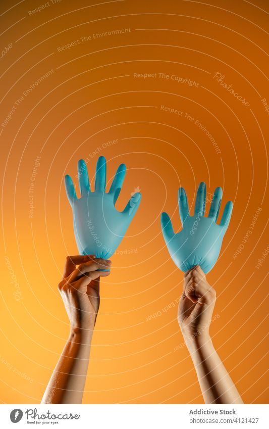 Crop person with glove balloons in studio wave hand gesture medical show surgical sign coronavirus protect concept creative fun arms raised covid 19 latex