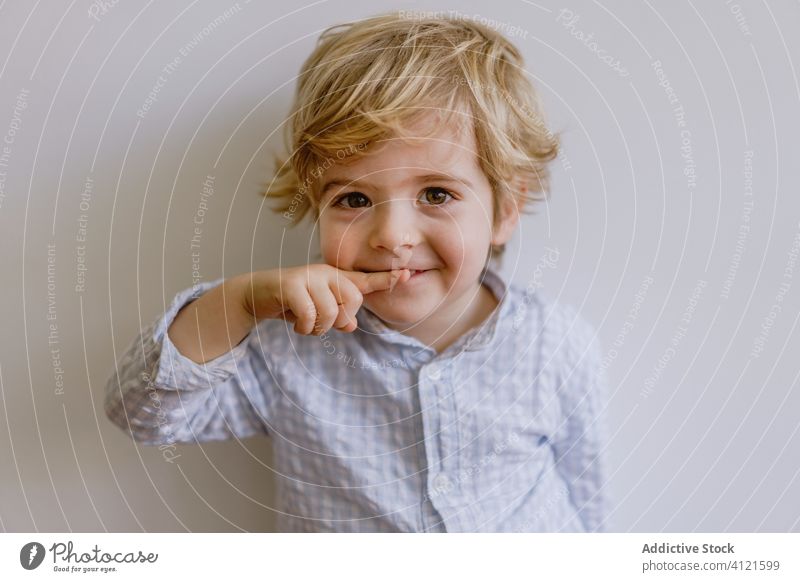 Delighted boy smiling and pointing at camera smile delight little kid adorable child content cheerful optimist cute childhood positive casual face expression