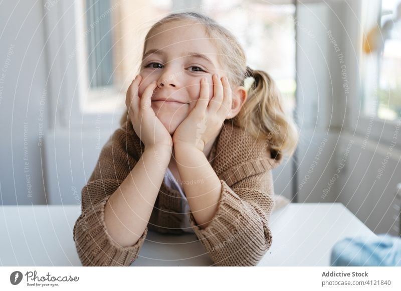 Happy little girl looking at camera in cozy home happy smile kindergarten kid lean on hand child charming portrait cute childhood adorable education joy