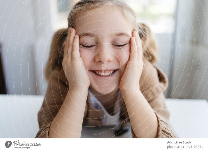 Happy little girl with closed eyes in cozy home happy smile kindergarten kid lean on hand child charming portrait cute childhood adorable education joy