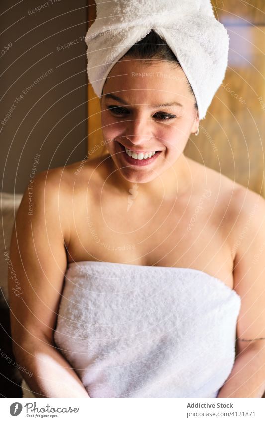Cheerful woman sitting in towel near door after taking bath body care shower wet laugh wellness cheerful glad satisfied happy enjoy friendly carefree pleasant