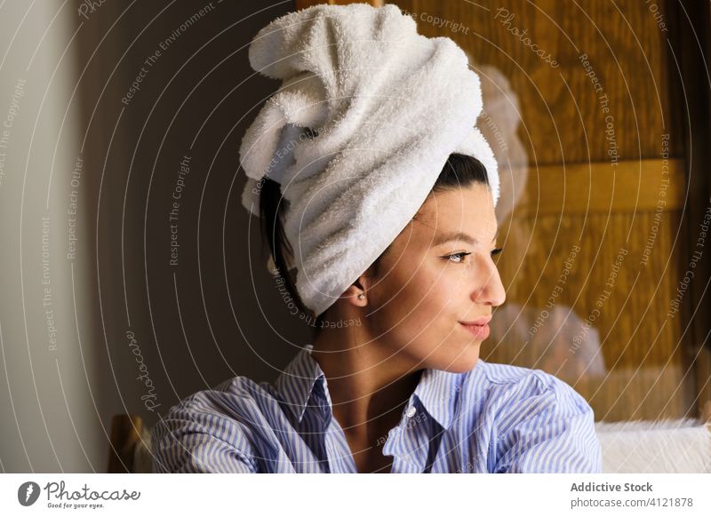 Happy woman with towel on head after bath at home toothy smile shower fresh clean happy morning hygiene relax comfort sunlight apartment cheerful positive