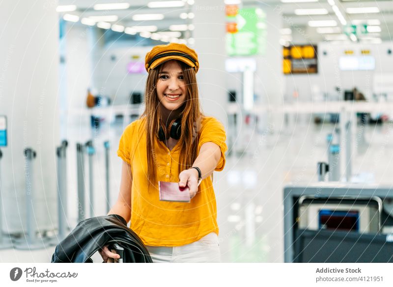Young happy female student checking in for flight at airport woman passport registration check in passenger departure glad trendy colorful terminal leave