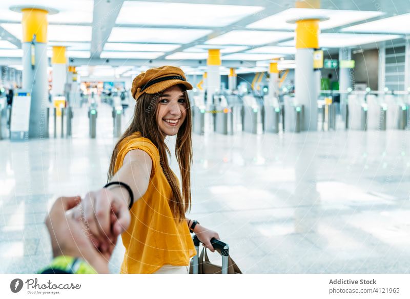 Cheerful female traveler holding hand of boyfriend before leaving into trip woman airport trendy follow me leave departure yellow toothy smile joy wait way