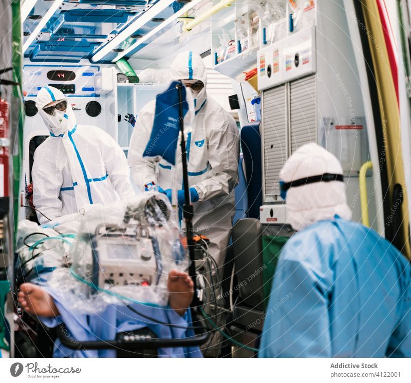 Interior of ambulance car with doctors in protective suit group uniform equipment patient service hospital clinic professional work vehicle health care mask