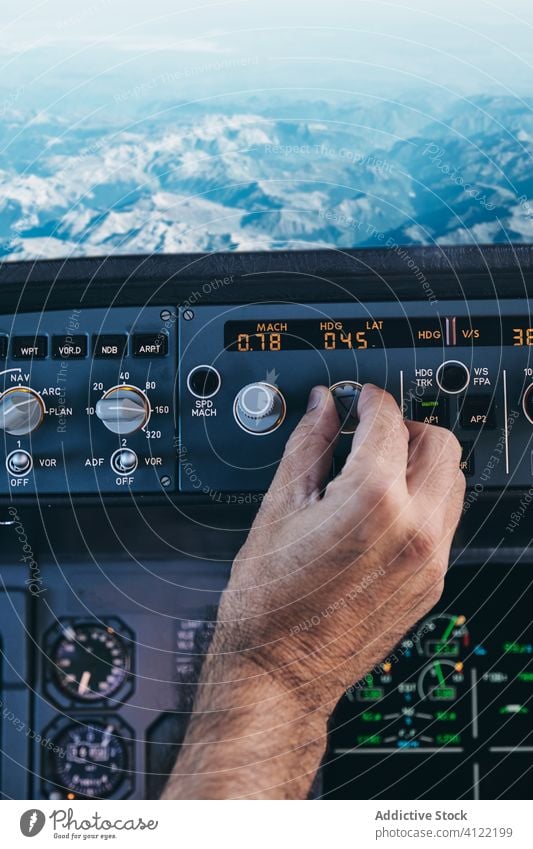 Pilot working with control console during flight pilot cockpit operate man hand switch airplane dashboard rock mountain equipment male aviator check modern