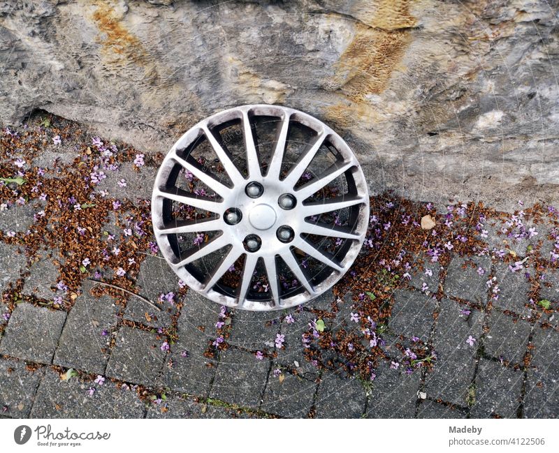 Hubcap with star-shaped design in the style of a light metal rim in autumn at the roadside in the old town of Oerlinghausen near Bielefeld at the Hermannsweg in the Teutoburg Forest in East Westphalia-Lippe