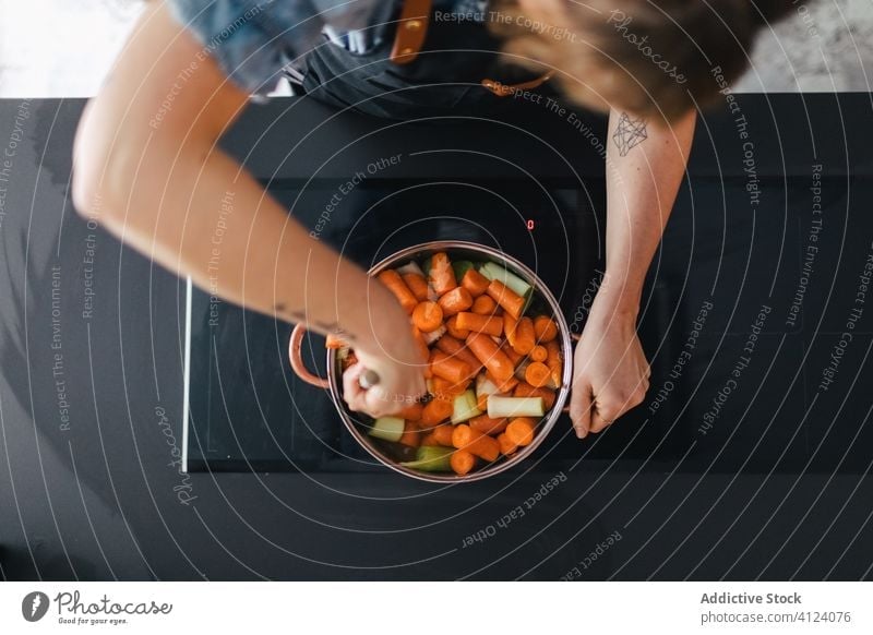 Woman cooking vegetable soup in kitchen dinner woman carrot stove stir saucepan apron prepare food modern kitchenware cuisine recipe home ingredient dish fresh