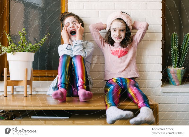 Happy little sisters having funny spa day at home children face mask laugh alike together playful skin care pajama happy relax scream childhood enjoy positive