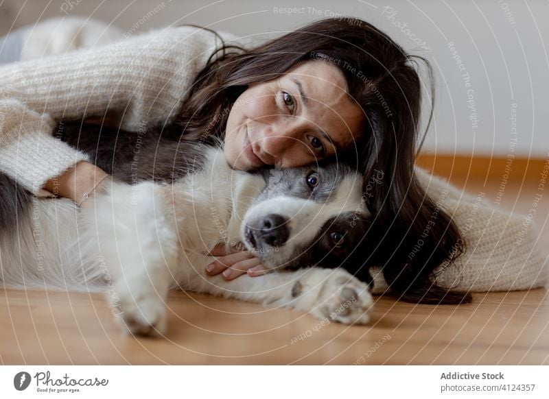 Happy woman embracing cute purebred gray white dog during rest on floor embrace hug care friendship pet adorable border collie together animal happy smile