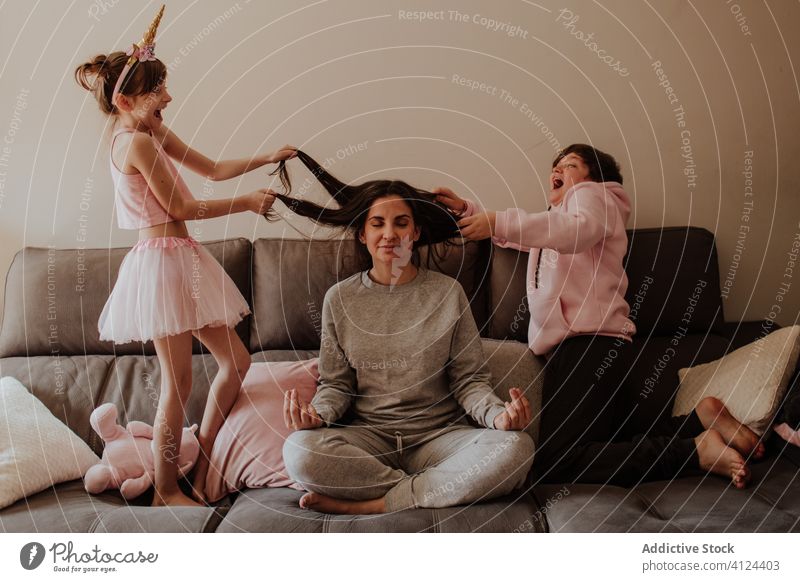 Children bothering meditating mother on couch children meditate sofa lotus pose pull scream fun together excited little girl teen boy kid woman mindfulness