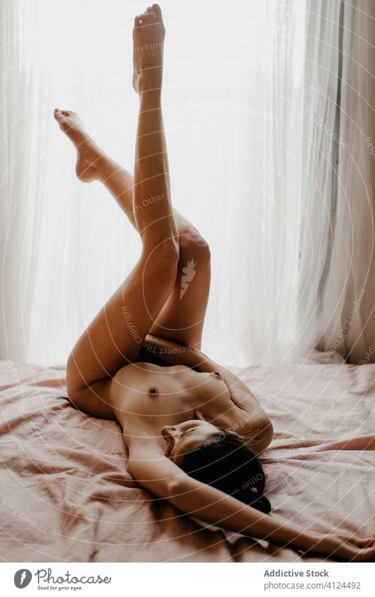 Nude woman lying on bed and masturbating